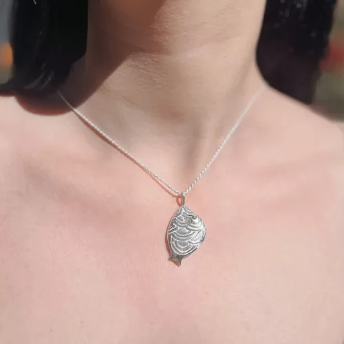 Dije de plata .925 con figura de pez chico ovalado con ondas por Teresa González.