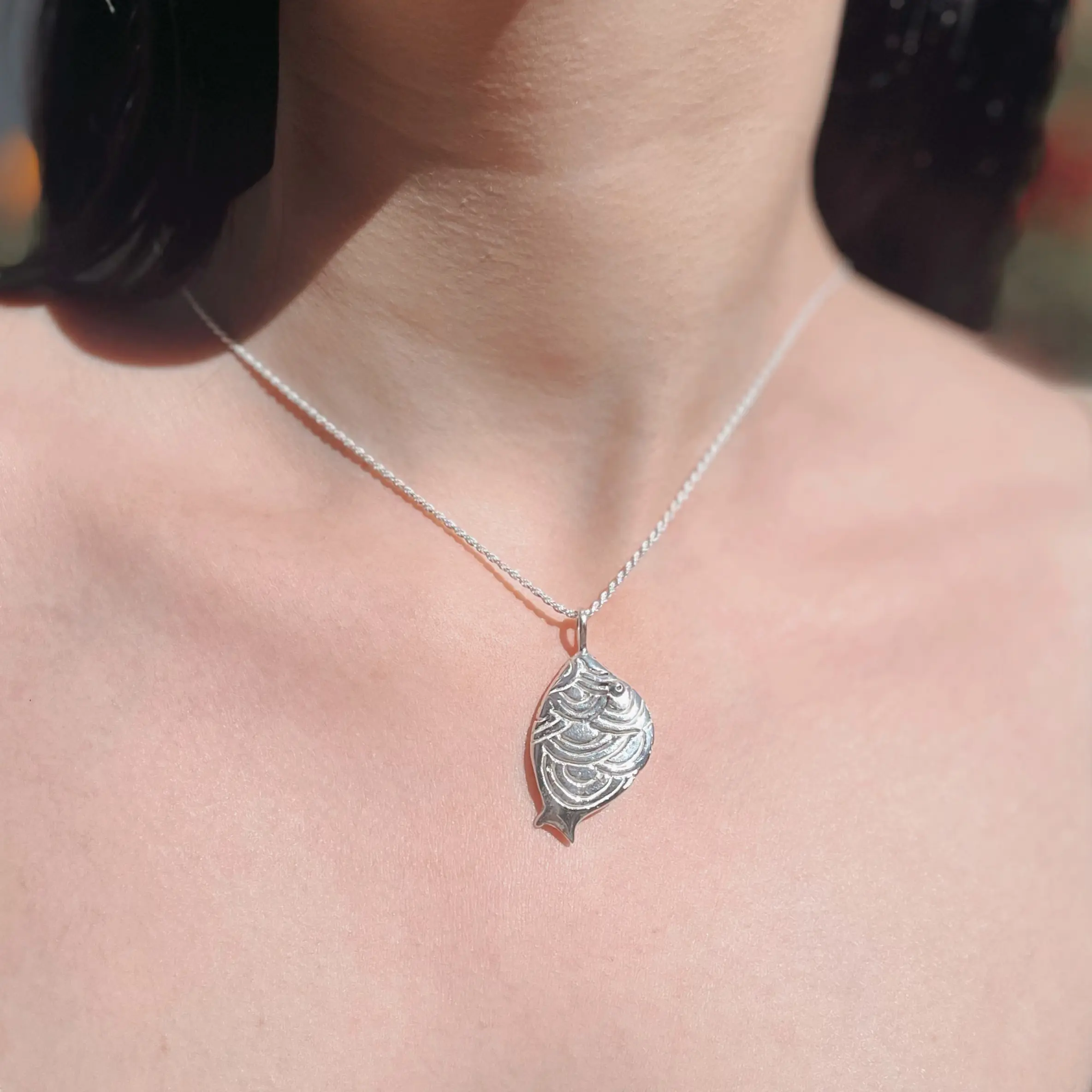 Dije de plata .925 con figura de pez chico ovalado con ondas por Teresa González.